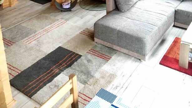 Ein gemütliches Blockhaus-Interieur mit einer Couch, einem Kamin, einer Treppe und einem Fenster.