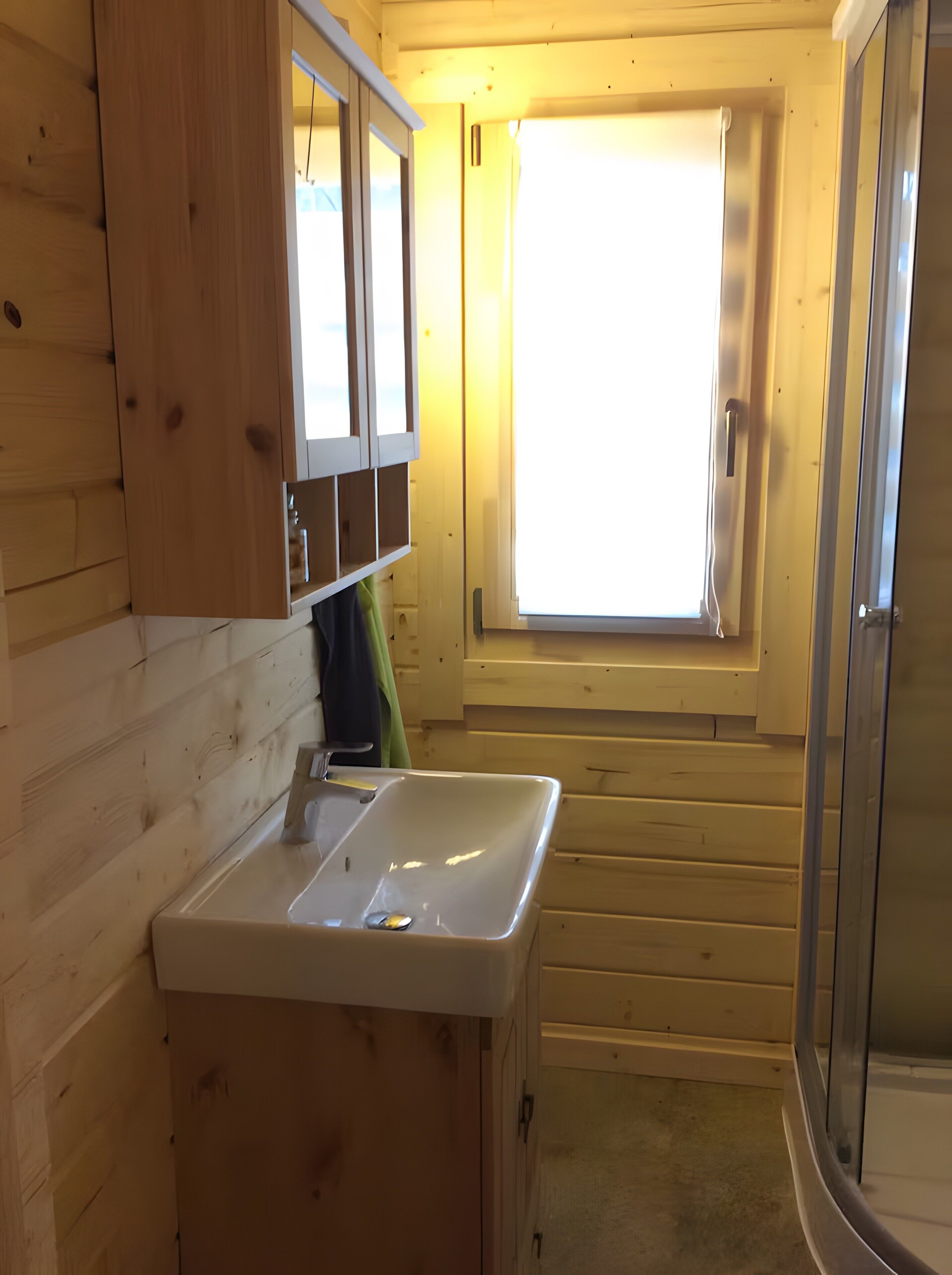 Ein Holzblockhaus-Innenraum mit Bad, Fenster und Waschbecken.