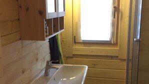Ein Interieur einer Holzhütte mit Badezimmer, Fenster und Waschbecken.