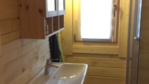 Ein Interieur einer Holzhütte mit Badezimmer, Fenster und Waschbecken.