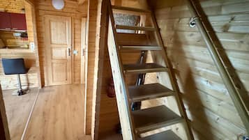 Een houten interieur met een trap, een keukenhoek en een stoel.