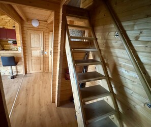 A wooden interior with a staircase, a kitchen area, and a chair. - Ferienhaus 'Summit Butze Hohegeiß Blockhütte' mit WLAN und Klimaanlage (Braunlage)