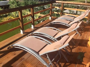 A wooden deck with lounge chairs and a view of a pond. - Ferienhaus 'Summit Butze Hohegeiß Blockhütte' mit WLAN und Klimaanlage (Braunlage)