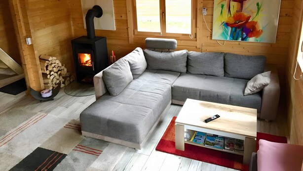 Ein gemütliches Blockhaus-Interieur mit einer Eckcouch, einem kleinen Tisch, einem Kamin und einem Bild an der Wand.