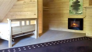 Ein Holzinnenraum mit einem Bett, einem Kamin und einem Gemälde einer Felsformation.