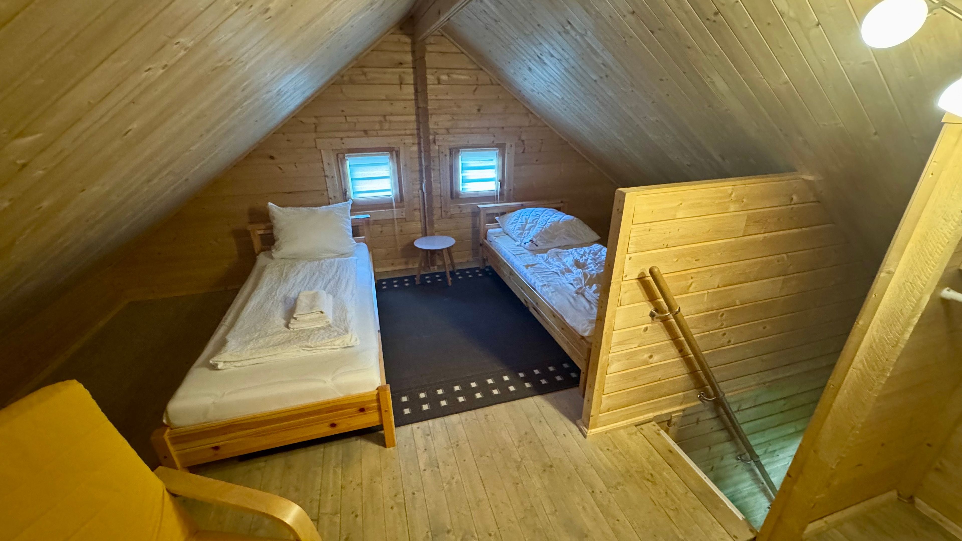 Ein kleines Schlafzimmer im Dachgeschoss, komplett mit zwei Betten, einem Tisch und einem Fenster.