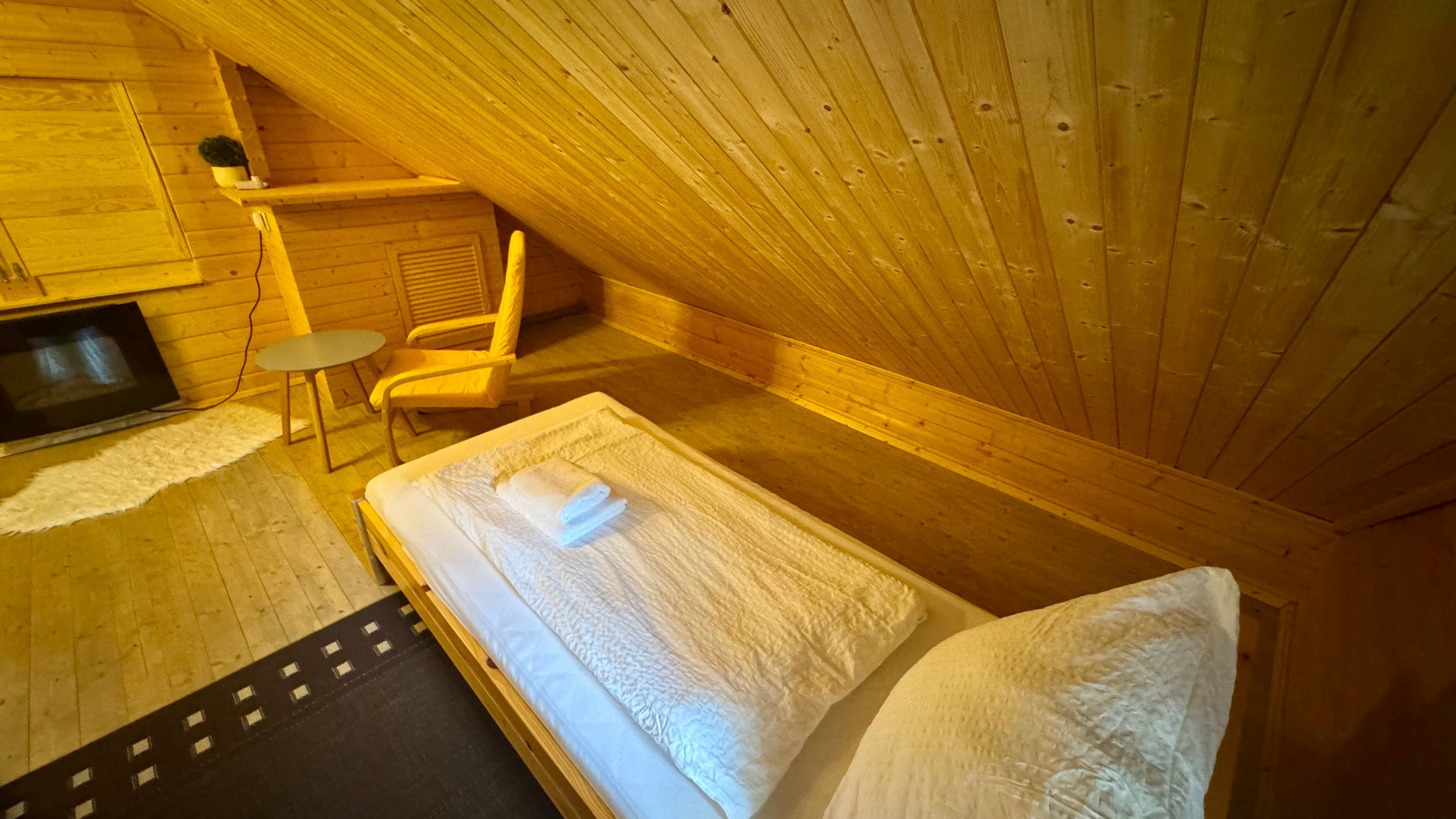 Un dormitorio acogedor en el ático, con cama, una silla y una pequeña mesa.