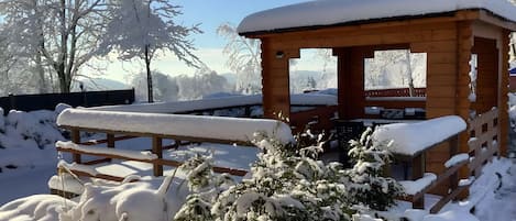 A wooden cabin with a snow-covered roof and a bench in front.