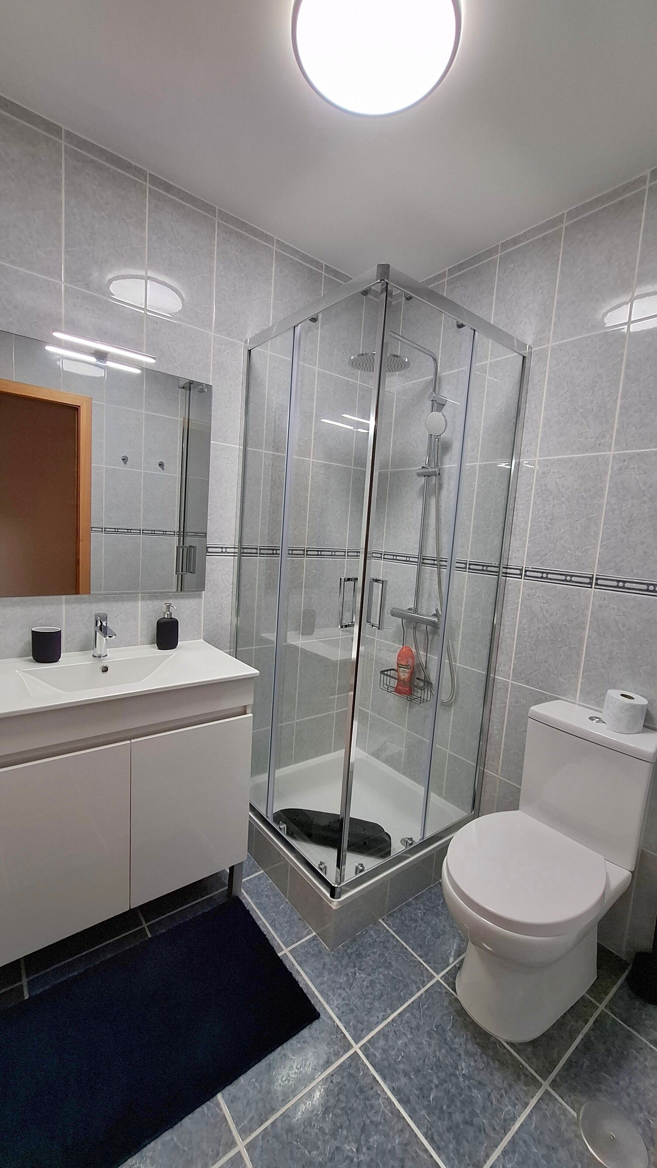 Une salle de bain moderne avec une douche à parois de verre, un lavabo blanc et des toilettes.