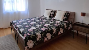 A bedroom with a bed, a nightstand, a lamp, and a window with curtains.