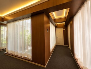 Un pasillo de hotel con piso alfombrado, paneles de madera y una puerta al final.