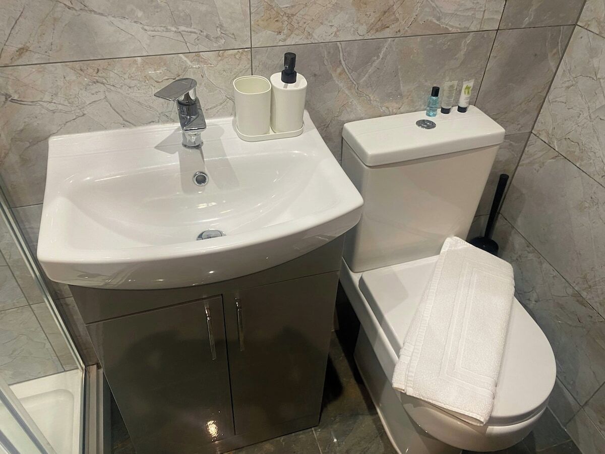 A bathroom with a sink, toilet, and a towel on the floor.