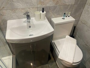 A bathroom with a sink, toilet, and a towel on the floor. - Accessible Double Studio | Near CBS Arena (Kitchenete (West Midlands)