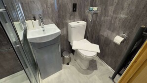 A modern bathroom with a toilet, sink, and a trash bin. - Accessible Double Studio | Near CBS Arena (Kitchenete (West Midlands)