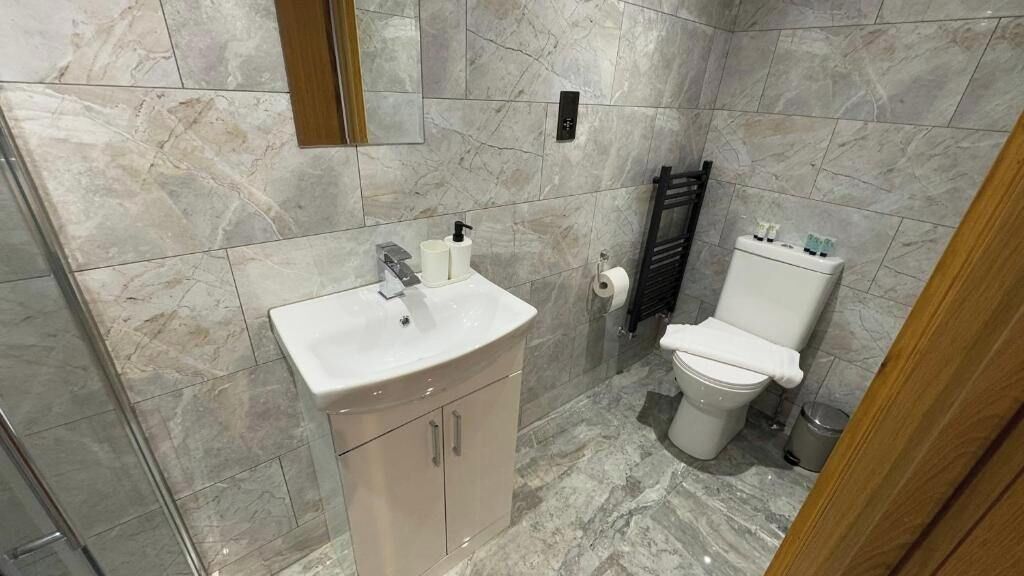A bathroom with a marble sink, a toilet, and a towel rack.