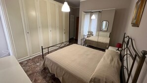 A bedroom with a bed, a wardrobe, a mirror, and a hanging light fixture. - Vrbo Property (Fondi)