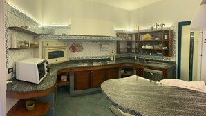 A compact kitchen with a microwave, oven, and built-in dishwasher. There are wooden cabinets and a granite countertop. - Vrbo Property (Fondi)