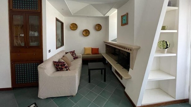 A living room with a sofa, a fireplace, and a dining table. - Vrbo Property (Fondi)