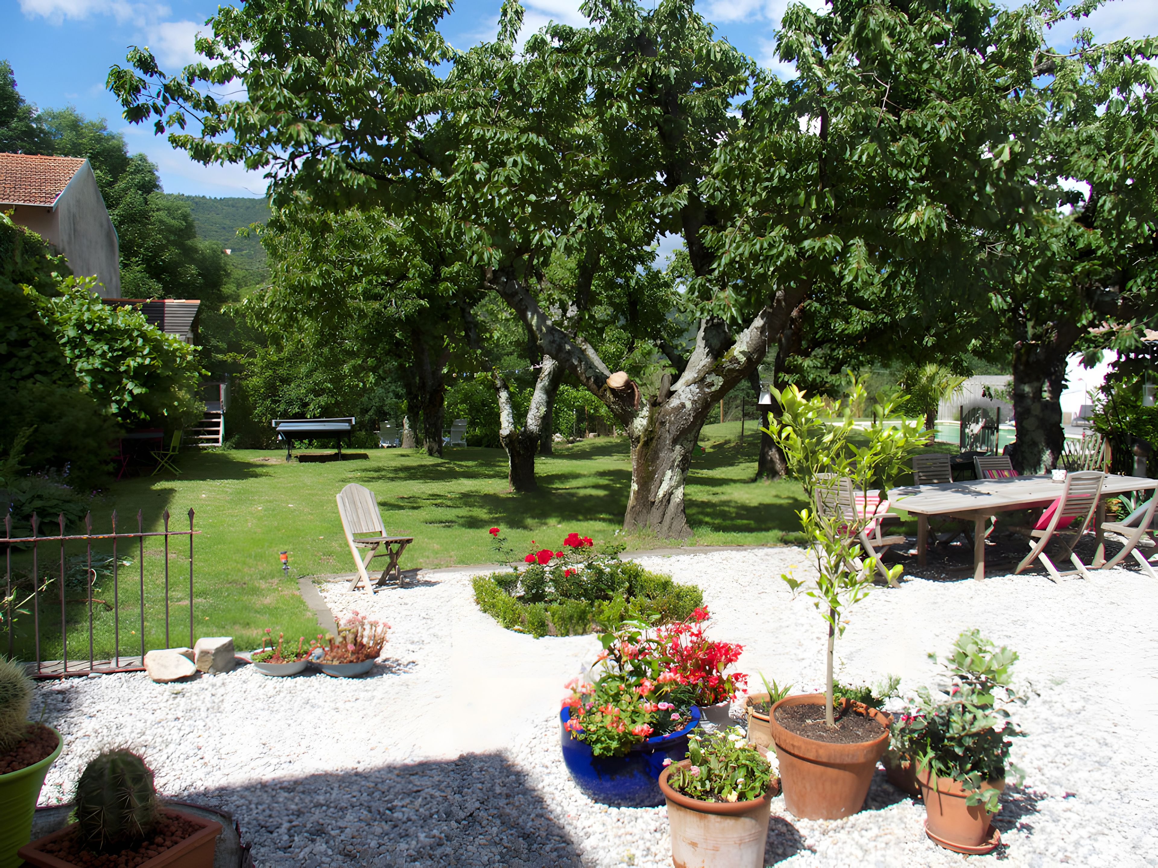 A garden with a variety of potted plants, a wooden bench, and a table with chairs.