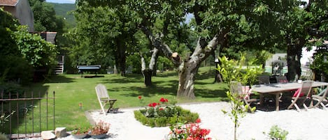 A garden with a variety of potted plants, a wooden bench, and a table with chairs.