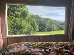 Een kamer met een groot raam met uitzicht op een bebost gebied.
