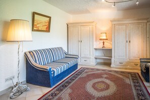 A living room with a sofa, a patterned rug, and white cabinets. - Apartment '104 Arnika' with Mountain View, Balcony and Wi-Fi (Riezlern)