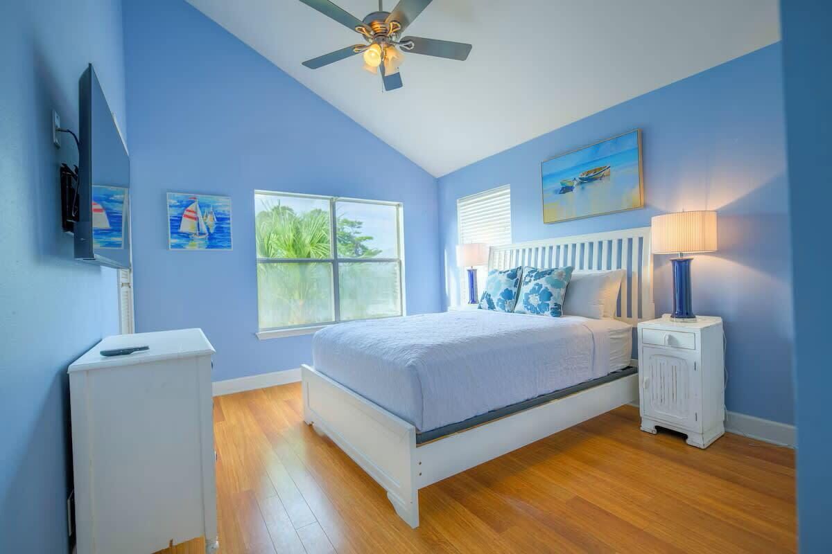 A bedroom with a bed, a ceiling fan, a window, and a nightstand.