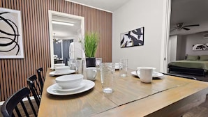 Uma área de refeições com uma mesa de madeira posta para quatro pessoas, rodeada por cadeiras.
