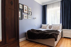 A bedroom with a bed, a nightstand, a dresser, and framed pictures on the wall. - Neptun View - Gdańsk Old Town  (Gdańsk)