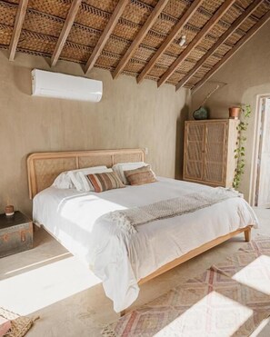 A bedroom with a wooden bed, a woven headboard, a woven wardrobe, and a potted plant. - La Fragata bungalows SAC (Los Organos)