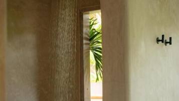 Um corredor estreito com parede texturizada e uma pequena janela com uma planta.
