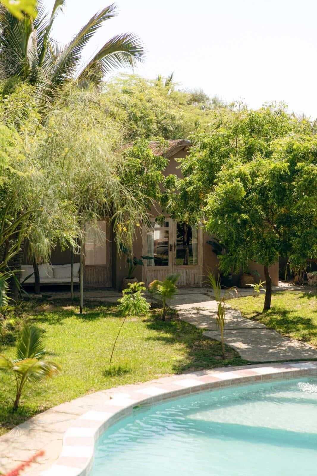 A poolside area with a clear view of a building with a covered patio and a door.