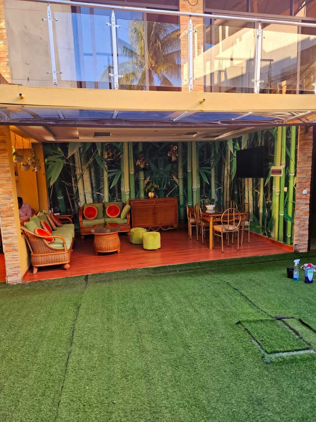 Un espace extérieur aménagé, abrité et doté de mobilier en osier, d’une table et de chaises.