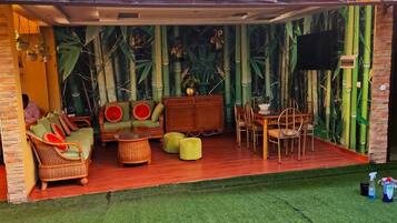 Un espace extérieur aménagé, abrité et doté de mobilier en osier, d’une table et de chaises.