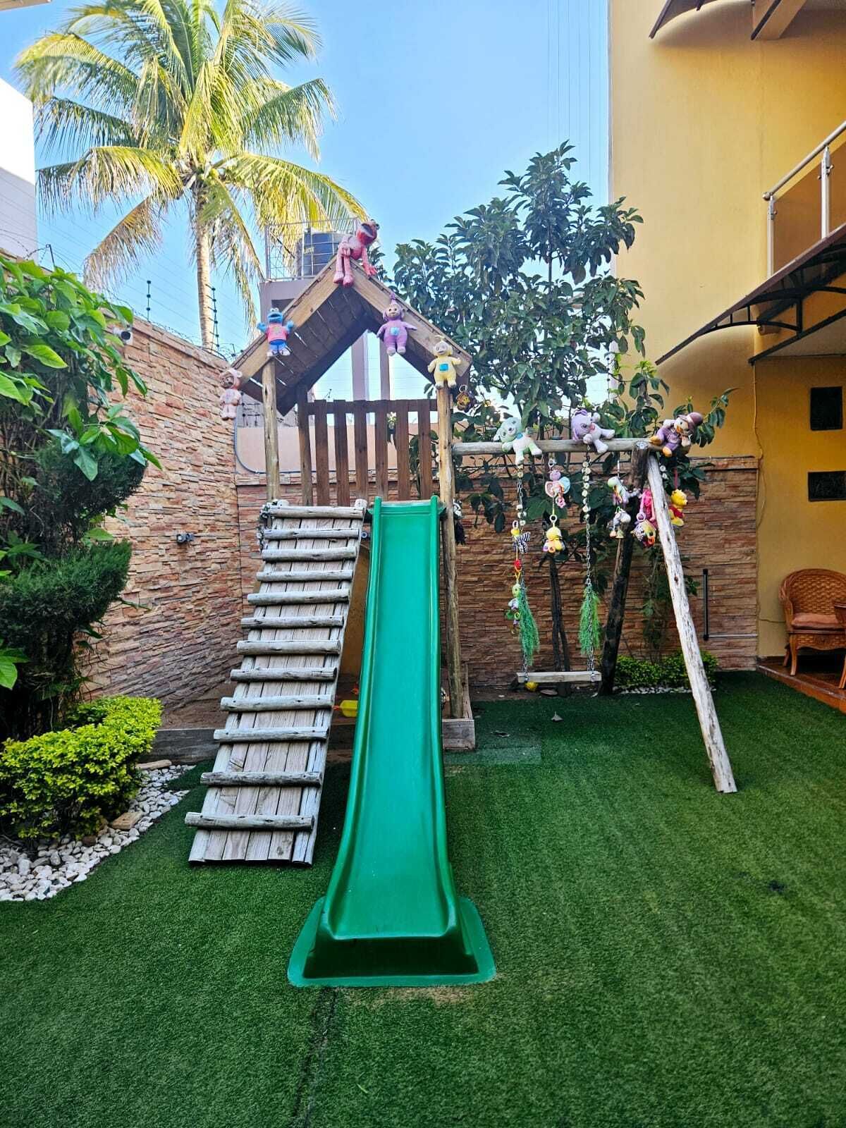 Un espace de jeux pour enfants avec un toboggan, une structure d’escalade et un petit pavillon.