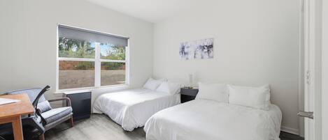 Ein Schlafzimmer mit zwei Betten, einem Schreibtisch und einem Sessel.