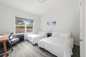 Une chambre avec deux lits, un bureau et une chaise.