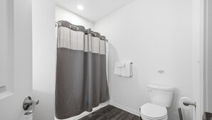 Een badkamer met toilet, douchegordijn, handdoekrek en een dweil.
