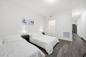 Habitació d'hotel amb dos llits, un quadre a la paret, una porta que dona a un passadís i una sortida d'aire a la paret.