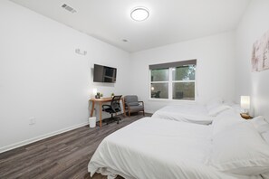 Ett hotellrum med två sängar, ett skrivbord med en stol, en tv och ett fönster.