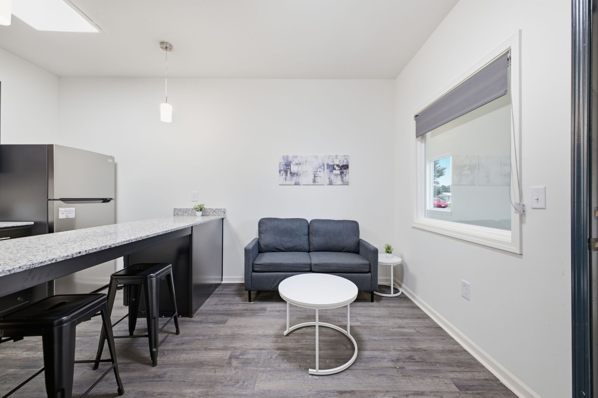 A compact kitchen with a built-in refrigerator, a bar counter, and a gray sofa.