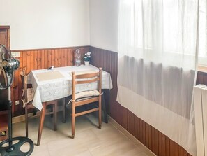 A dining area with a table and chairs, a fan, a bottle, and a potted plant. - Klaus Studio - Schignano (Occagno)