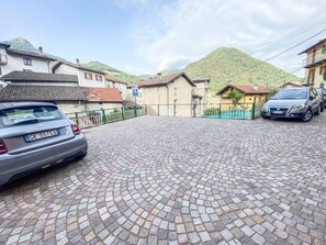 A paved courtyard with a car parked on the left, surrounded by buildings with traditional architecture. - Klaus Studio - Schignano (Occagno)