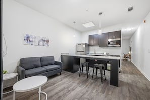 Een moderne keuken met een grijze bank, een eettafel en een bar voorzien van krukken.