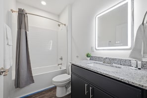 Een moderne badkamer met een douche, toilet en wastafel met spiegel.