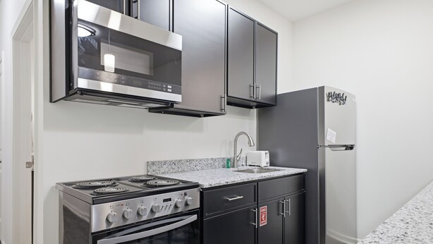 Una cocina equipada con estufa, horno, microondas y refrigerador.