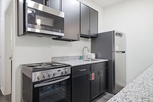 A kitchen with a stove, oven, microwave, and refrigerator.