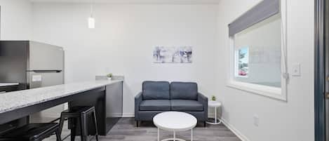 Eine moderne Küche mit Barbereich, einem grauen Sofa und einem kleinen runden Tisch.
