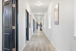 A hallway with a light-colored floor, white walls, and doors on both sides.