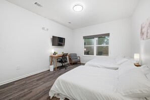 Ett hotellrum med två sängar, ett skrivbord med en stol, en tv och ett fönster.